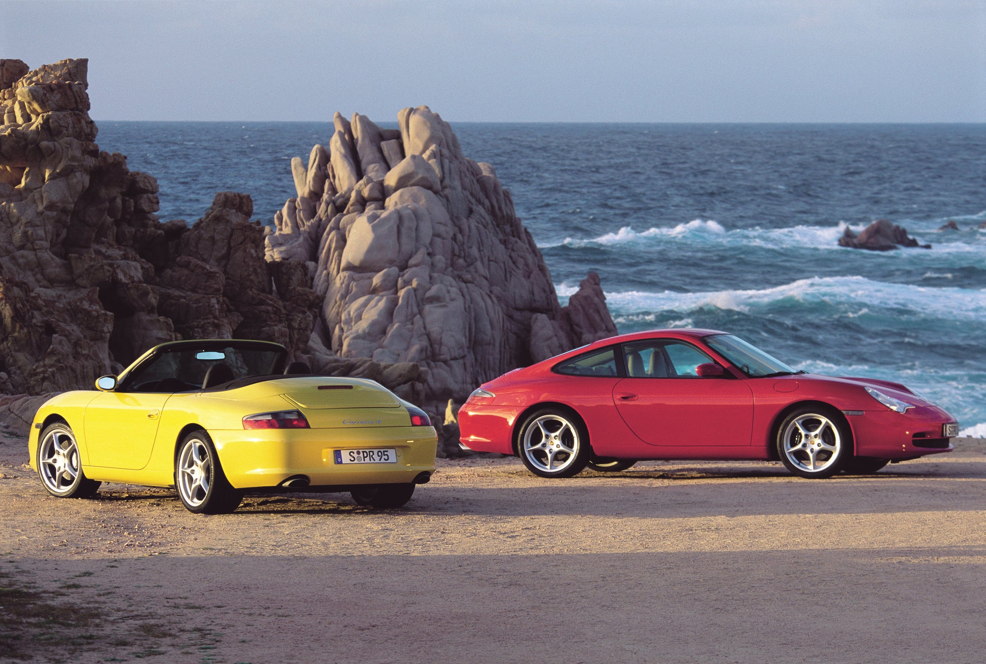 Red and yellow 911 (type 996) Porsches photographed at the beach